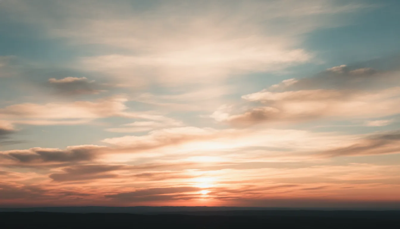 Sunrise sky with glowing rose and peach clouds above distant hills